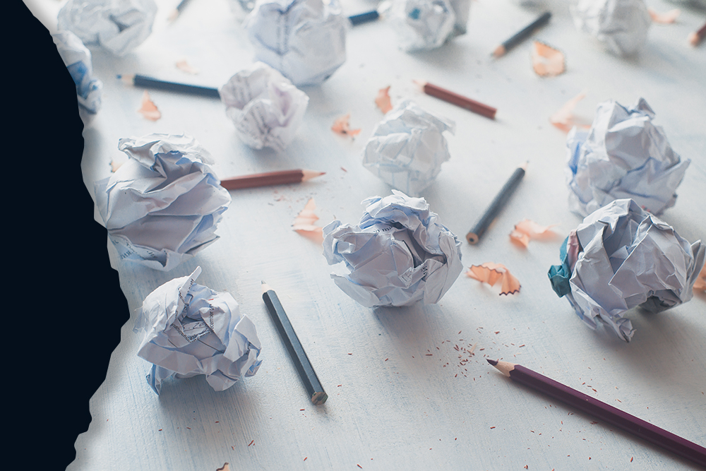 Close-up of crumpled paper balls on a white wooden background with pencils and pencil shavings. Creative writing concept.